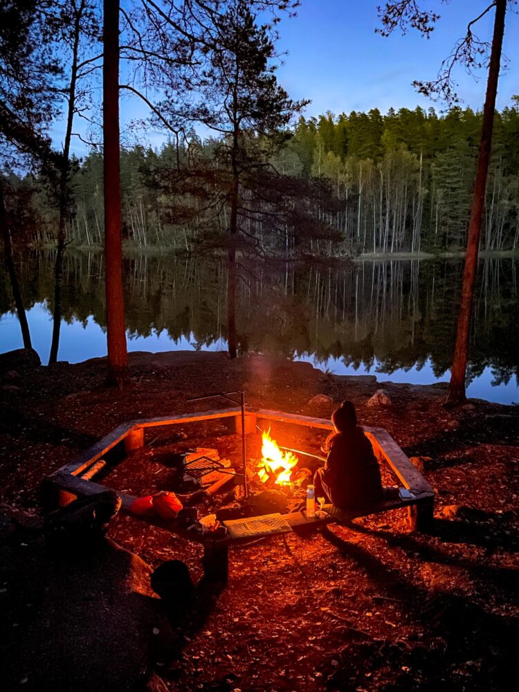 Person sitting by a campfire on a camping trip in Nuuksio National Park